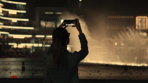 Счастливая девушка снимает видео с фонтанами и иллюминациями — стоковое видео