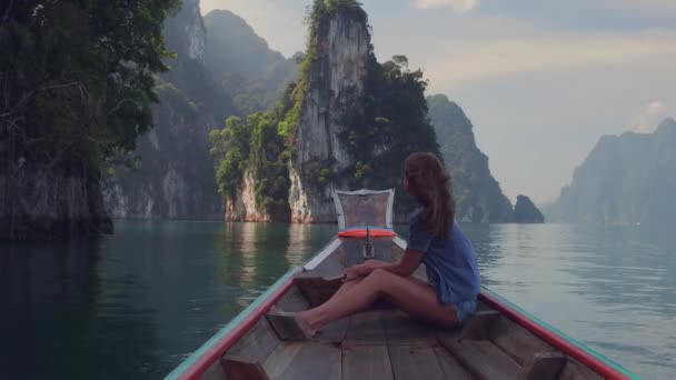 Video gaya hidup dari wanita cantik perjalanan duduk di kayu panjang ekor perahu di tebing batu kapur tropis. Jelajahi dan konsep liburan. Danau Khao Sok, Thailand . — Stok Video