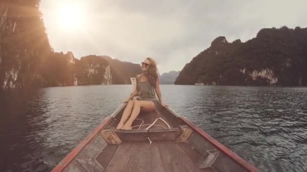 Lifestyle video of pretty travel woman sitting in wood long tail boat on tropical limestone cliffs . Explore and vacation concept. Khao Sok lake, Thailand. — Stock Video