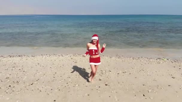 AERIAL. Hermosa mujer feliz en la señora Claus custume en la playa tropical, Navidad y año nuevo concepto de vacaciones . — Vídeo de stock