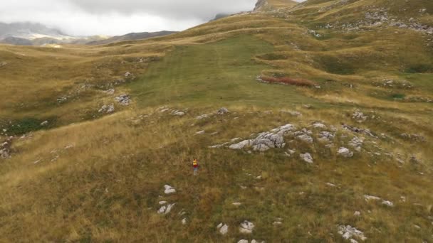 Vista aérea de un joven y solitario rastreador turístico caminando por las colinas — Vídeos de Stock