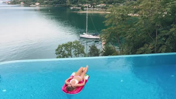 AERIAL. Encantadora joven mujer caucásica rubia en gafas de sol y bañador — Vídeos de Stock