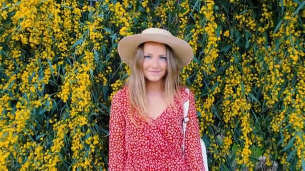 Блондинка в солом'яному капелюсі на тлі жовтих квітів. Сонячний день і красива природа. концепція моди . — стокове відео