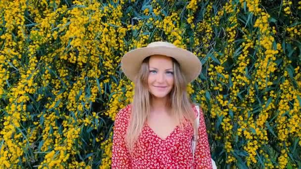 Блондинка в солом'яному капелюсі на тлі жовтих квітів. Сонячний день і красива природа. концепція моди . — стокове відео