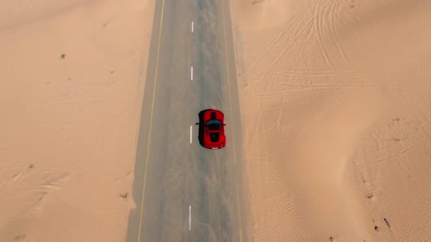 Flygfoto Röd racerbil ridning på öknen vägen i Förenade Arabemiraten. — Stockvideo