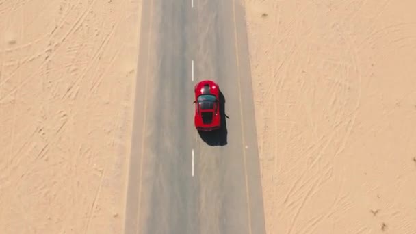 Flygfoto Röd racerbil ridning på öknen vägen i Förenade Arabemiraten. — Stockvideo