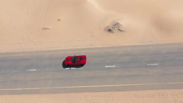 Повітряний вид Червоний гоночний автомобіль їде пустельною дорогою в ОАЕ.. — стокове відео