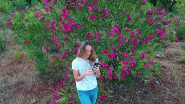 Giovane donna felice felice sorridente godendo primavera giornata estiva con fiori sullo sfondo — Video Stock