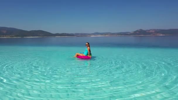 Una hermosa chica en un colchón en un mar de impresionante pureza. — Vídeos de Stock