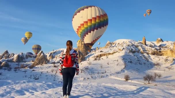 Frau hebt die Hände und blickt auf Heißluftballons in Kappadokien — Stockvideo