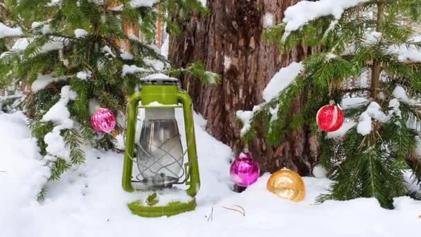 Juletids koncept. Snö faller ner i skogen med nyårsbollar. — Stockvideo