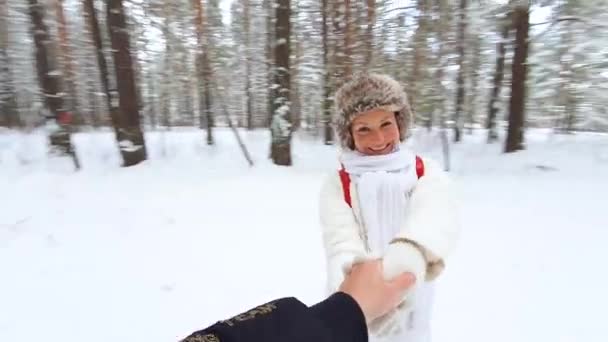 En ung vacker flicka i vinterskogen virvlar med sin pojkvän och faller i snön.. Ögon glöder av lycka. — Stockvideo