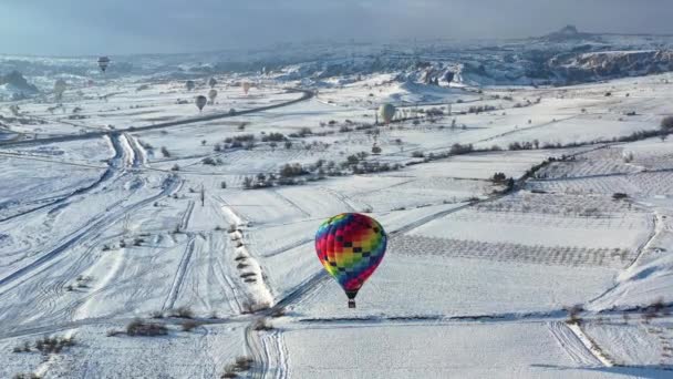 AERIAL. Top view to the colourful hot air balloon flying above winter landscape. — Stock Video