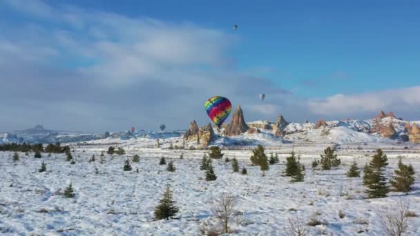 AERIAL. Horní pohled na barevný horkovzdušný balón letící nad zimní krajinou. — Stock video