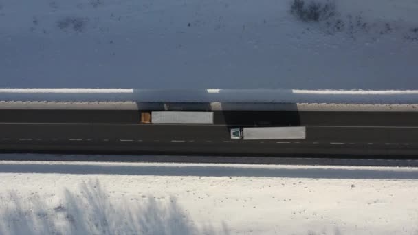 AEREALE. Vista dall'alto della colonna di camion che guida sulla strada innevata in inverno. — Video Stock