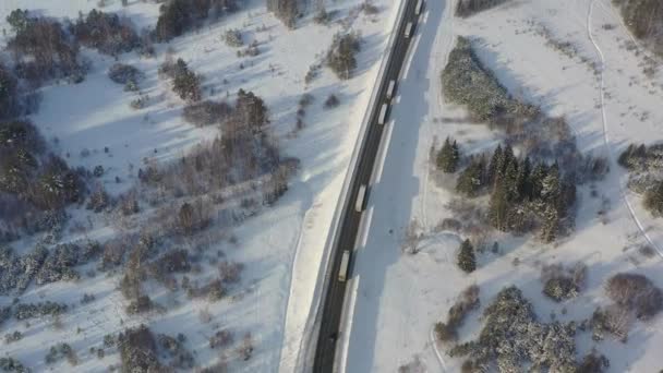 AERIAL. Vista superior a la columna de camiones que conduce en el camino de nieve en tiempo de invierno. — Vídeos de Stock