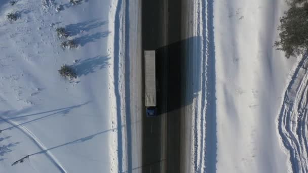 AERİAL. Kış zamanı kar yolunda giden kamyonun üst görüntüsü. Teslimat konsepti — Stok video