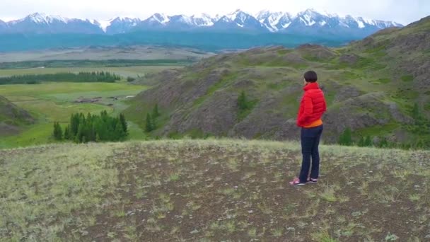 Une randonneuse debout fièrement sur le sommet d'une montagne par une journée froide et nuageuse. Femme debout au sommet de la montagne. Gros plan aérien . — Video