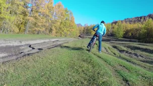 Una chica monta una bicicleta a lo largo de un camino forestal . — Vídeo de stock