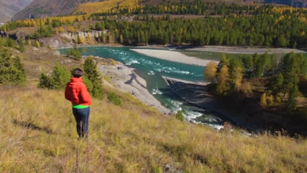 Uma mulher está junto ao rio com vista para as montanhas — Vídeo de Stock