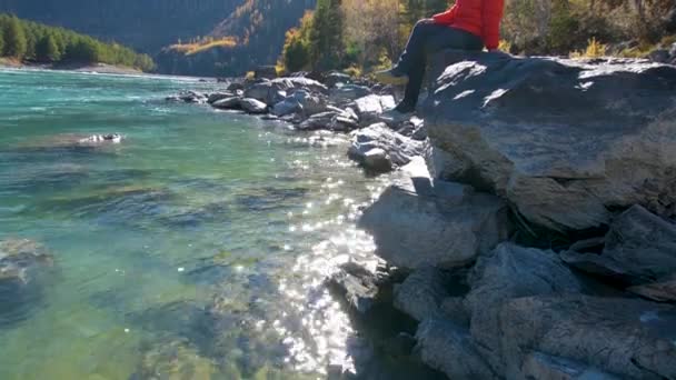 Una donna siede vicino al fiume con vista sulle montagne — Video Stock