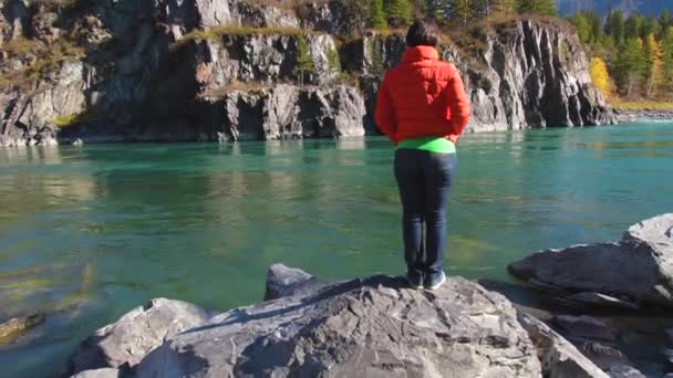 Una donna si trova vicino al fiume con vista sulle montagne — Video Stock