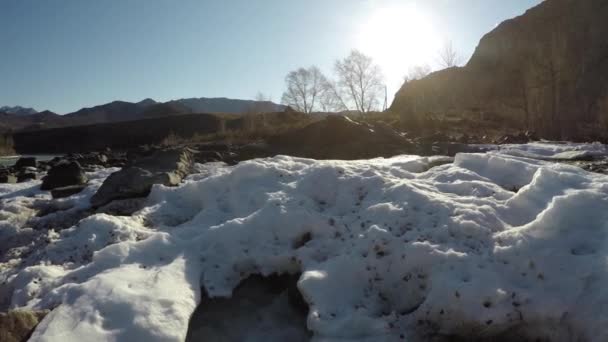 Wody źródlane w strumieniu, śnieg leży w dolinie, słońce świeci — Wideo stockowe