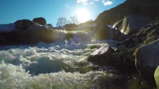 Bronwater in de beek, de sneeuw ligt in de vallei, de zon schijnt — Stockvideo