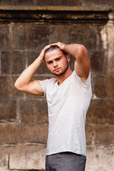 Athletic blond boy  in a T-shirt against the background of an evening city