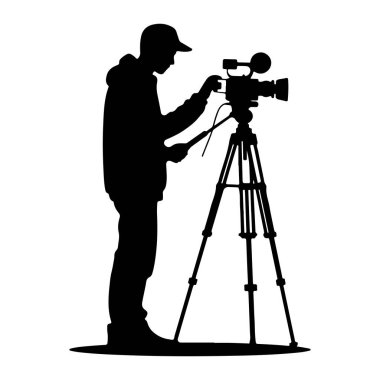 Beyzbol şapkası ve kapüşonlu kapüşonlu giyen birinin siyah silueti, tripoda monte edilmiş profesyonel bir kameranın solunda duruyor. Kameraya bağlı bir kol tutan kişi, onu çalıştırıyormuş gibi görünüyor. Kameranın lensi ve mikrosu var.