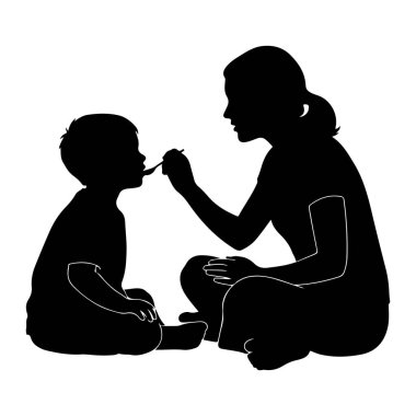 Siyah siluet bir kadın oturuyor ve küçük bir çocuğu kaşıkla besliyor. Çocuk yemek yemek için ağzı açık bir şekilde yerde kadına dönük oturuyor. Kadın kaşığı tutuyor ve çocuğun ağzına doğru getiriyor. Şey...
