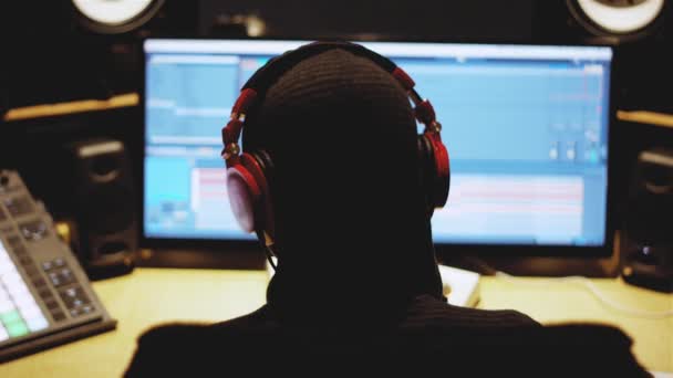 Музыкальный продюсер с наушниками, работающими в треке перед компьютером — стоковое видео