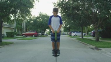 Ağır çekim çocuğun gülümseyen ve kameraya bakarak bir pogo çubuk üzerinde zıplayan