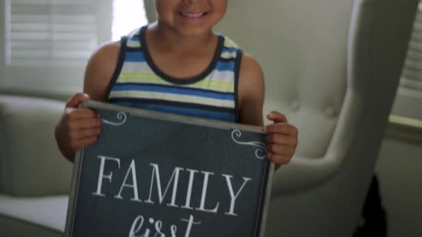 Slow Motion del niño mirando a la cámara y sosteniendo un cartel que dice "La familia primero " — Vídeos de Stock