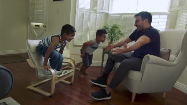 Slow motion van twee jongens in vaders armen springen en knuffelen hem thuis — Stockvideo