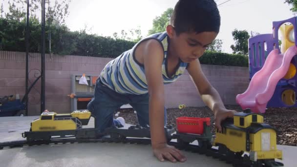 Movimiento lento de un niño jugando con un tren en un patio trasero — Vídeos de Stock