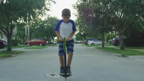 Slow motion of kid jumping on a pogo stick around neighborhood — Stock Video