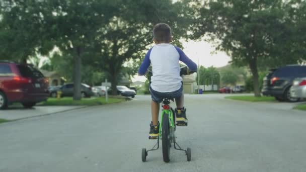 Movimento lento por trás do garoto andando de bicicleta em uma rua do bairro — Vídeo de Stock