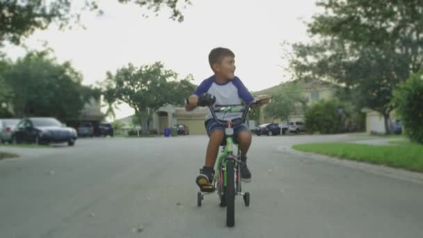 Movimiento lento del niño montando su bicicleta y mirando alrededor del vecindario — Vídeos de Stock