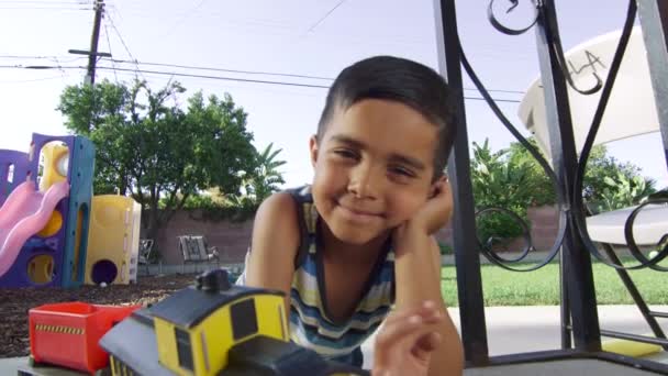 Slow Motion Primer plano del chico sonriendo a la cámara con juguetes alrededor — Vídeo de stock