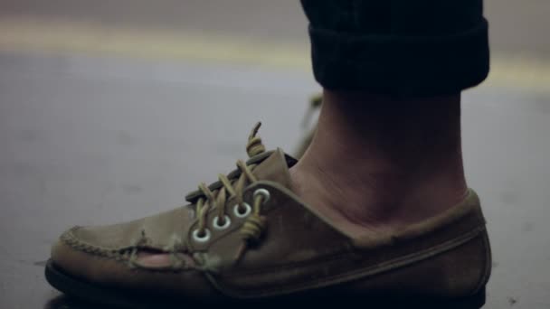 Медленное движение сломанной обуви человека, пока он ждет на станции метро — стоковое видео