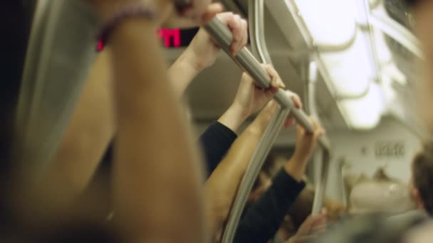 Movimento lento das mãos das pessoas segurando os trilhos dentro de um trem em movimento — Vídeo de Stock