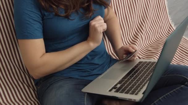 Movimento lento da mulher na frente do laptop segurando cartão de crédito e sorrindo — Vídeo de Stock