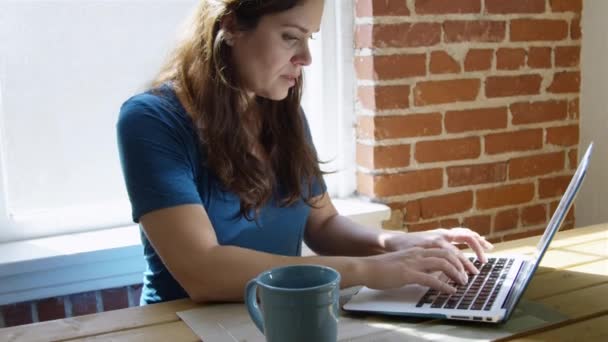 慢动作的妇女使用她的笔记本电脑和一杯咖啡在早上 — 图库视频影像