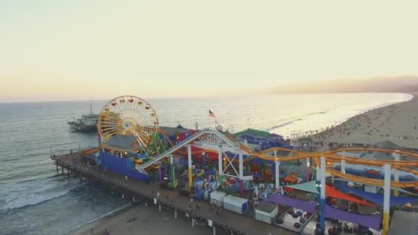 Повітряний постріл над їде в Santa Monica Pier рухається в напрямку океану під час заходу сонця — стокове відео