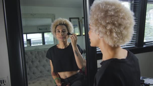 Медленное движение счастливой трансгендерной женщины, наносящей макияж перед зеркалом — стоковое видео