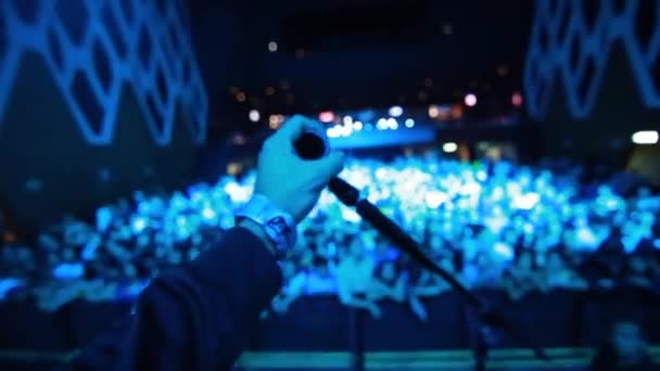 Сінгер руки, схопив мікрофон стояти на сцені з натовпу і вентилятори в передній — стокове відео