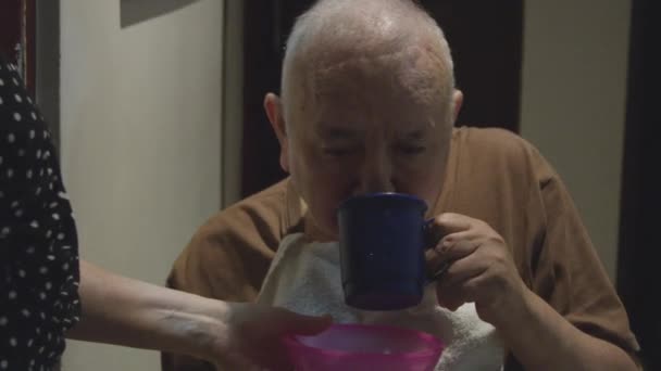Медленное движение старика, берущего воду из чашки и плюющего в тарелку — стоковое видео