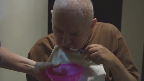 Повільний рух старого чистить зуби тарілкою, що тримається за нього — стокове відео