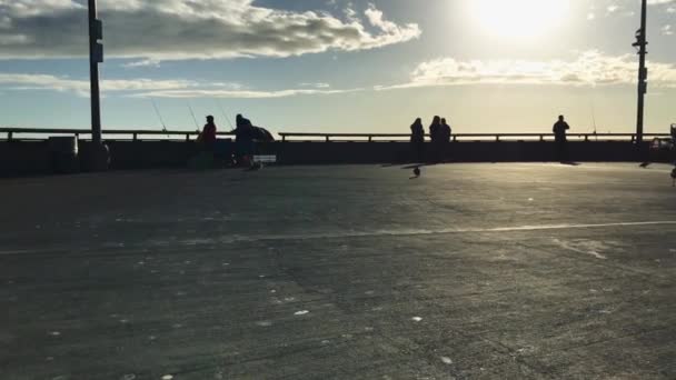 Bir iskelede Balık tutma günbatımı sırasında insan siluetleri — Stok video